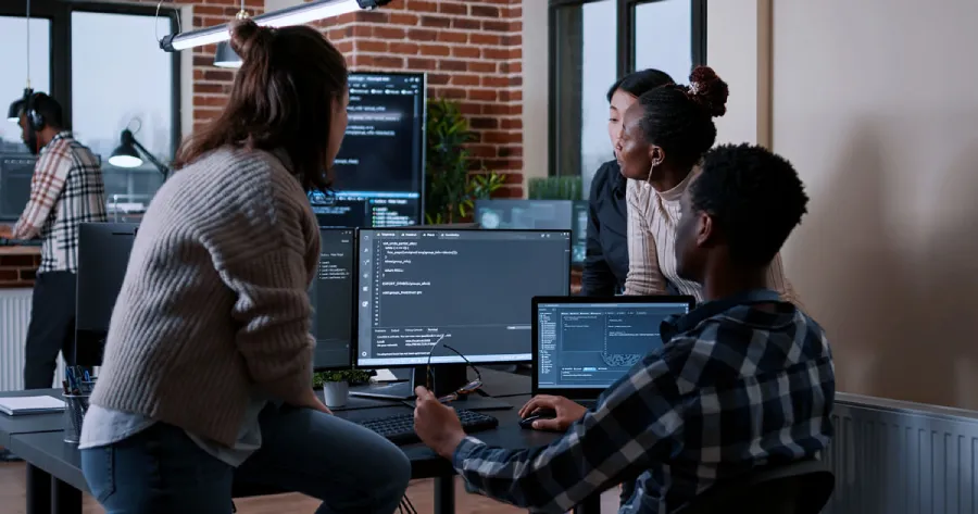 A team looking at multiple desktop screens. 