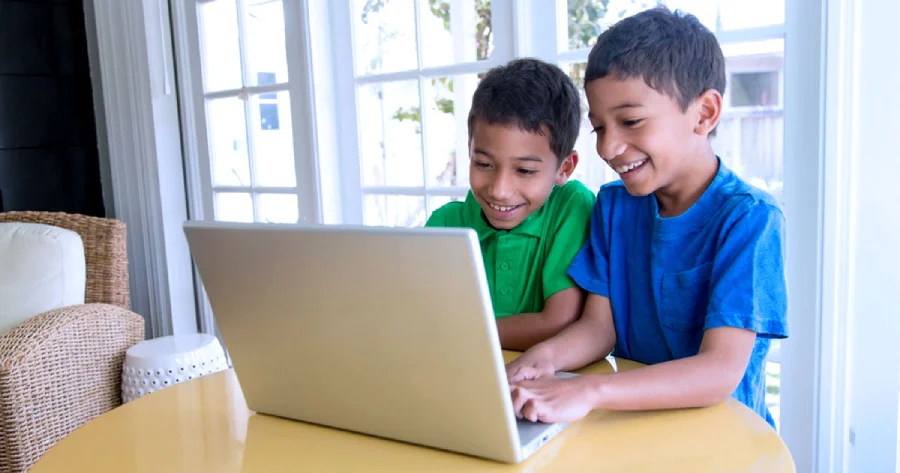 Two children playing on a laptop. 