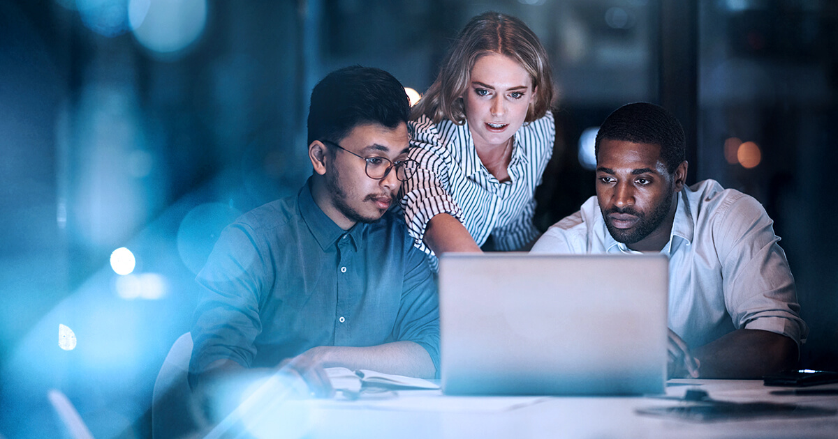  Two men and one woman looking at a laptop screen together.