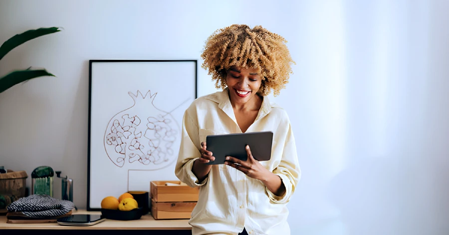 An African-American woman standing while looking at a digital tablet.