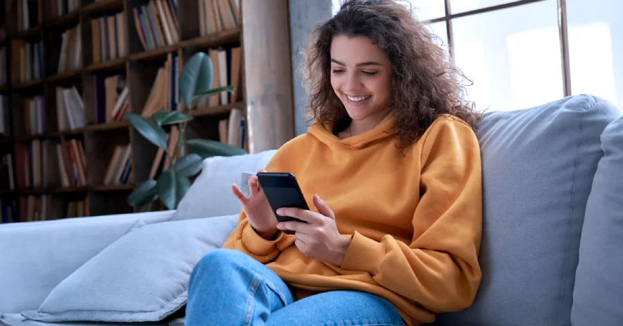  A happy Hispanic teen girl using a mobile learning platform on her smartphone. 