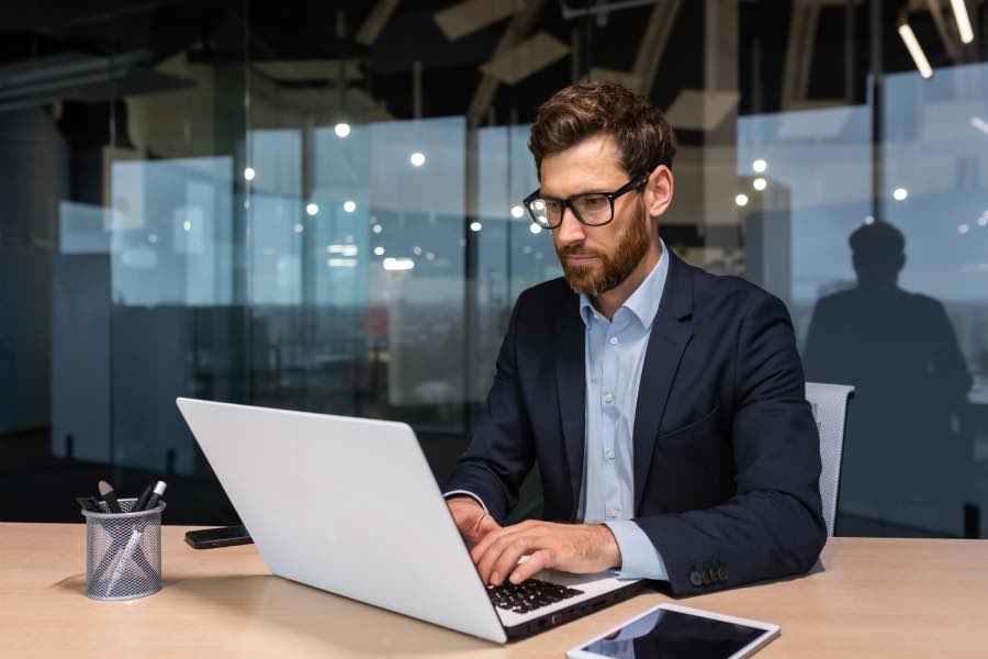 A working professional working on a laptop in a modern office setting, highlighting the importance of AI career readiness for school districts.