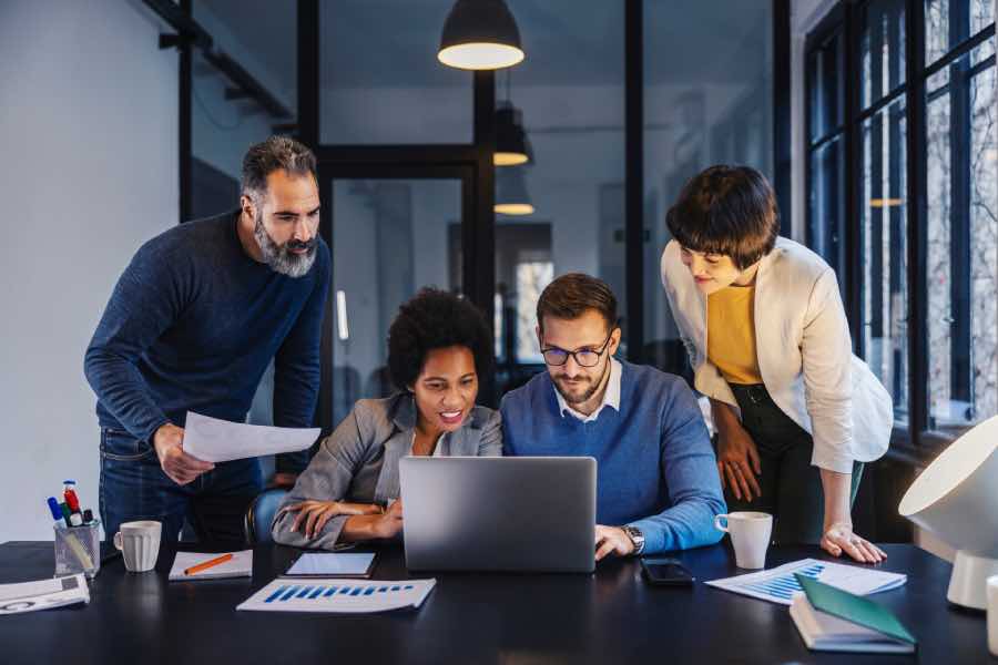 An edtech product team reviewing project data on a laptop together, highlighting the edtech product delivery process and planning in a modern office setting.