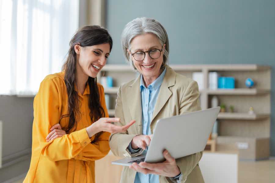 Two professionals reviewing title data on a laptop in an office setting, discussing improvements in ONIX metadata quality for UK publisher workflows.