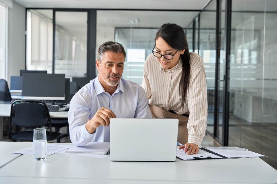 Two professionals reviewing content on a laptop in an office setting, while discussing UK copyright and AI for educational publishers.