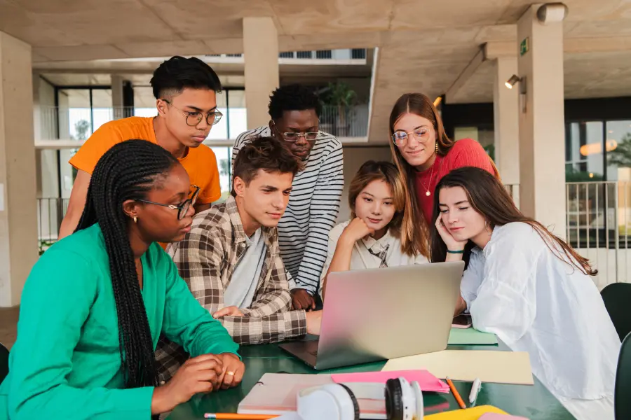 A diverse group of learners learning from a laptop during an educational content development session in a modern learning space.