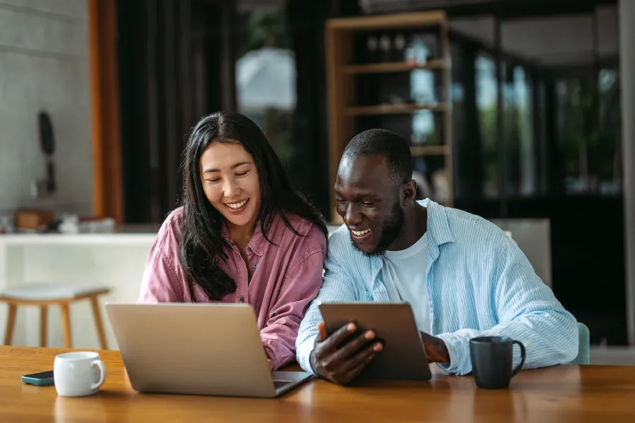 Two colleagues reviewing digital content on a laptop and tablet, representing collaborative existing content transformation in a modern workspace.